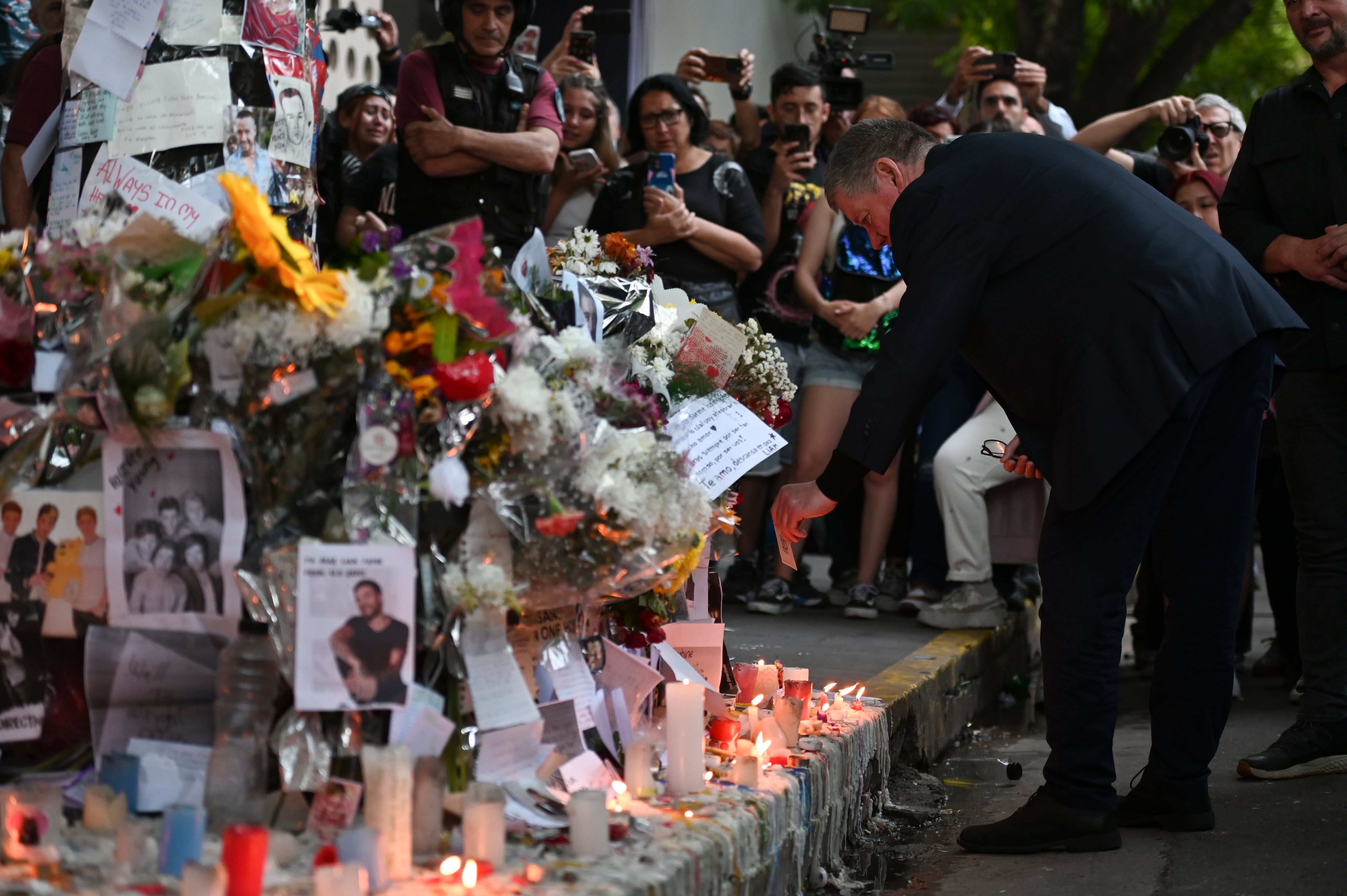 Geoff Payne, a la derecha, padre del exintegrante de One Direction, el cantante Liam Payne, visita un altar improvisado fuera del hotel Casa Sur Hotel donde el artista pop británico murió al precipitarse desde un balcón, en Buenos Aires, Argentina, el viernes 18 de octubre de 2024. (AP Foto/Mario de Fina)