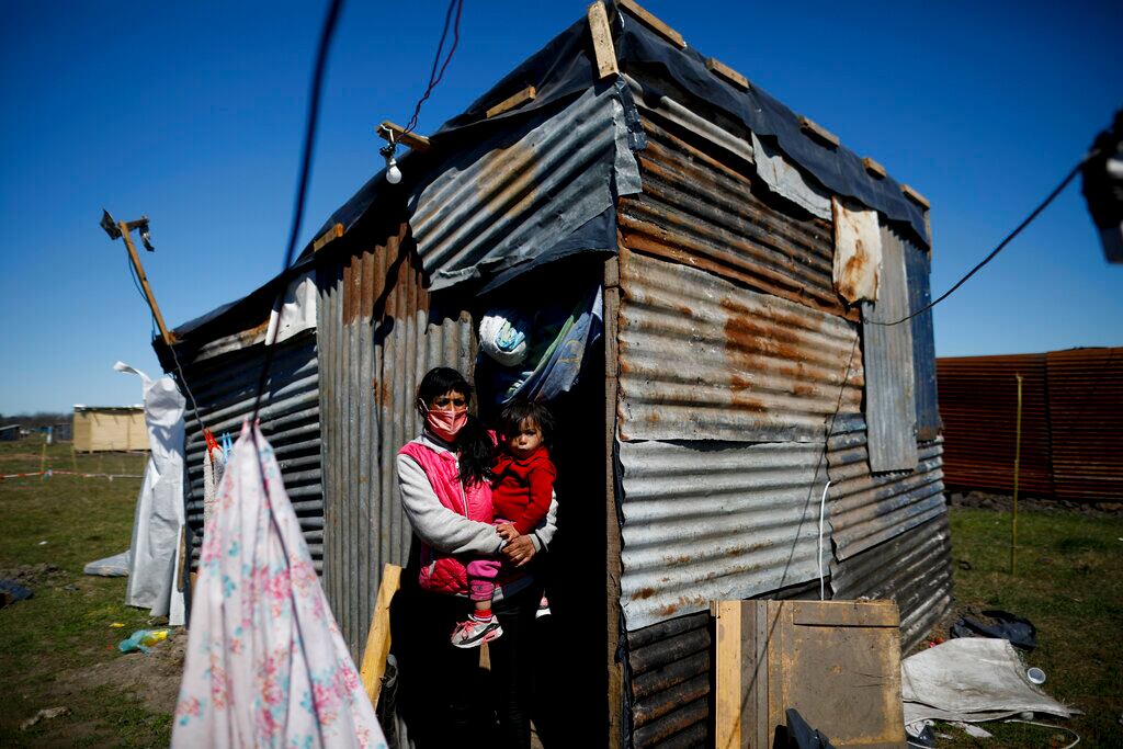 Cecilia Ávila sostiene a su hija Triana frente a su casa improvisada en un campamento de ocupantes ilegales en Guernica, provincia de Buenos Aires. (AP Foto/Natacha Pisarenko)