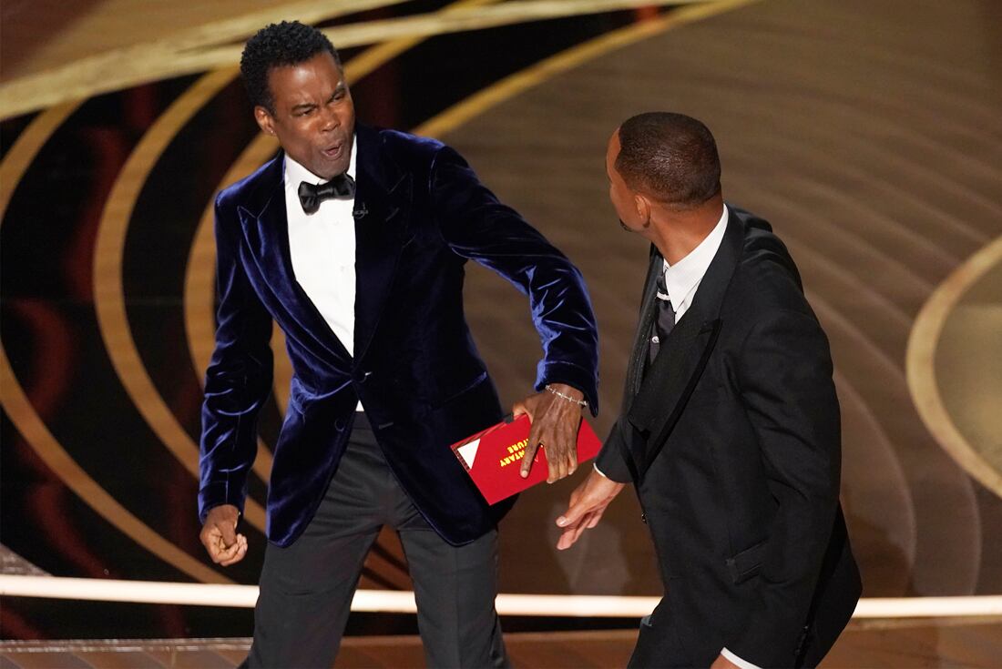 presenter Chris Rock, left, reacts after being hit on stage by Will Smith while presenting the award for best documentary feature at the Oscars on Sunday, March 27, 2022, at the Dolby Theatre in Los Angeles. (AP Photo/Chris Pizzello)