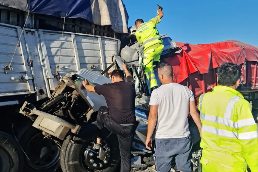 Los rescatistas trabajan en el lugar para sacar a uno de los camioneros que quedó atrapado en la cabina