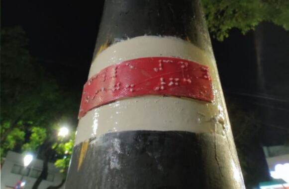 Estudiantes platenses colocaron en un poste de luz frente a su escuela una señalética en braille.