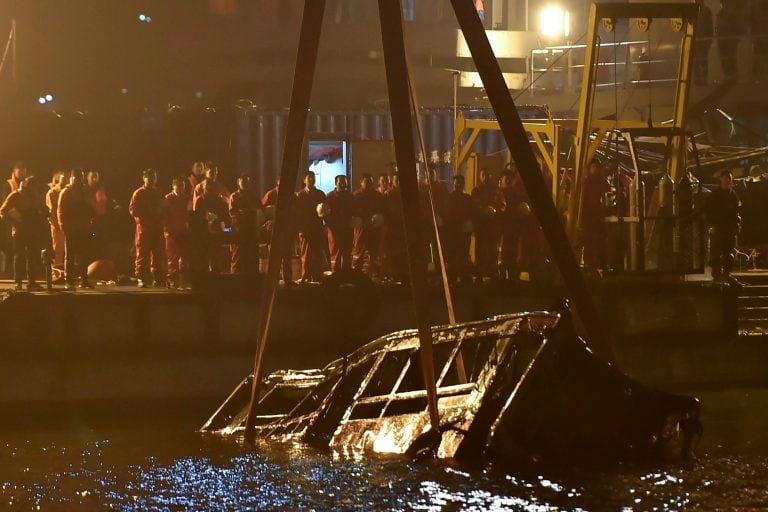 El autobús es sacado del río Yangtze por una grúa flotante. Crédito: Photo by STR / AFP.