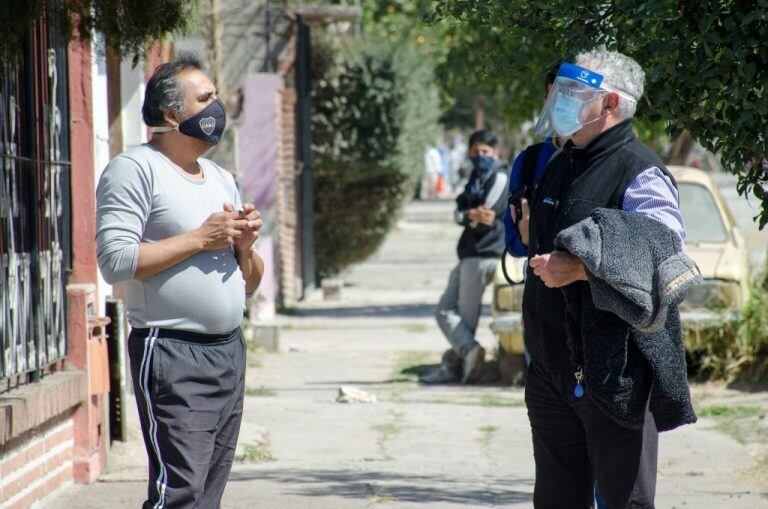 El ministro Bouhid en diálogo con un vecino durante el operativo "puerta a puerta" en busca de pacientes sintomáticos de Covid-19.