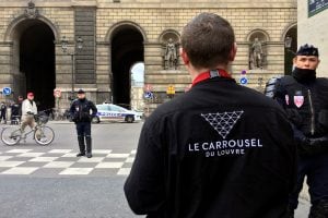 An employee of the Carrousel du Louvre waits outside the museum protected by police forces in Paris, Friday, Feb. 3, 2017. A knife-wielding man shouting "Allahu akbar" attacked French soldiers on patrol near the Louvre Museum Friday in what officials desc