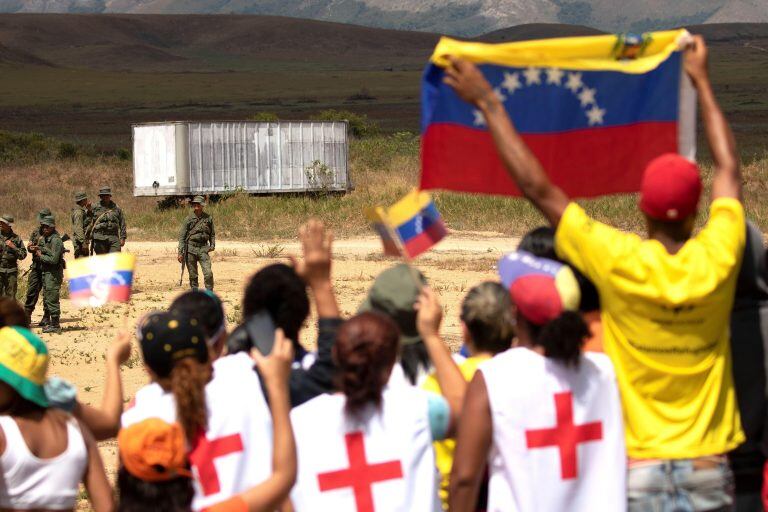 AME7796. PACARAIMA (BRASIL), 23/02/2019.- Manifestantes antichavistas intentan conversar con miembros de la Guardia Nacional Bolivariana (GNB, policía militarizada) de Venezuela, quienes montan guardia este sábado en el paso fronterizo ubicado en la localidad de Pacaraima, en el límite fronterizo entre Brasil y Venezuela, cerrado desde el jueves por orden del Gobierno de Nicolás Maduro. Unos 300 manifestantes antichavistas se aglomeran en el paso fronterizo entre ambos países, en la localidad de Pacaraima, a la espera de que los militares venezolanos abran el acceso para que los dos vehículos, cargados con alimentos y medicinas, entren en Venezuela. EFE/Joédson Alves