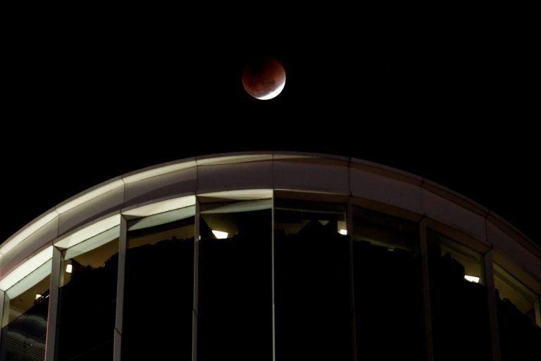 A "super blood blue moon" is seen during an eclipse, behind an office building in Hong Kong, China January 31, 2018. REUTERS/Bobby Yip