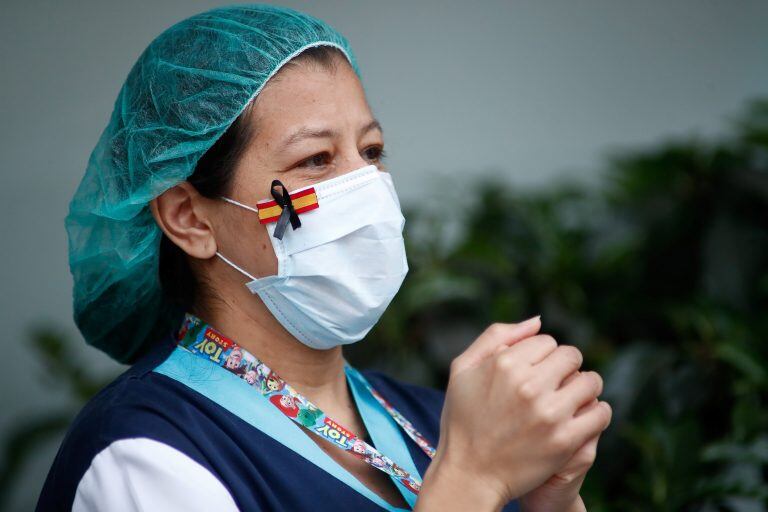 Una sanitaria, con una mascarilla que muestra una bandera de España con un lazo negro de luto por los fallecidos por coronavirus. (Foto: EFE).