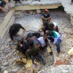 Residents try to rescue a man trapped under the rubble of a two-storey shop after it collapsed during an earthquake in Pidie Jaya, Aceh province on December 7, 2016. 
The death toll from a powerful earthquake that struck western Indonesia on December 7 has nearly doubled to 97, the military said, as more bodies were pulled from the rubble of scores of shattered buildings. / AFP PHOTO / AQIEN ABDULLAH