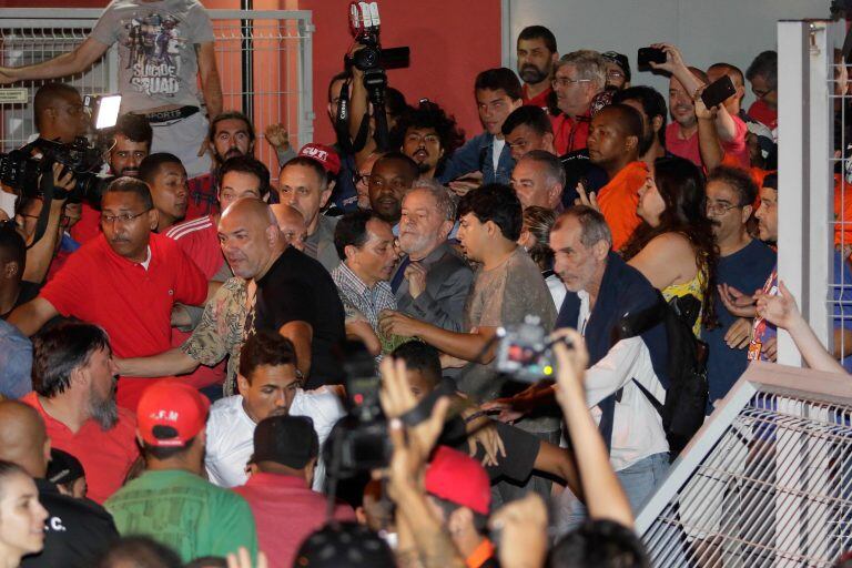 Brazilian former President Luiz Inacio Lula da Silva (C) leaves the Metallurgical Union on his way to Sao Pablo airport, in Sao Bernardo do Campo, Sao Paulo state, Brazil, on April 07, 2018.
Brazil's election frontrunner and controversial leftist icon said Saturday that he will comply with an arrest warrant to start a 12-year sentence for corruption. "I will comply with their warrant," he told a crowd of supporters. / AFP PHOTO / Frame Photo / Thiago Bernardes