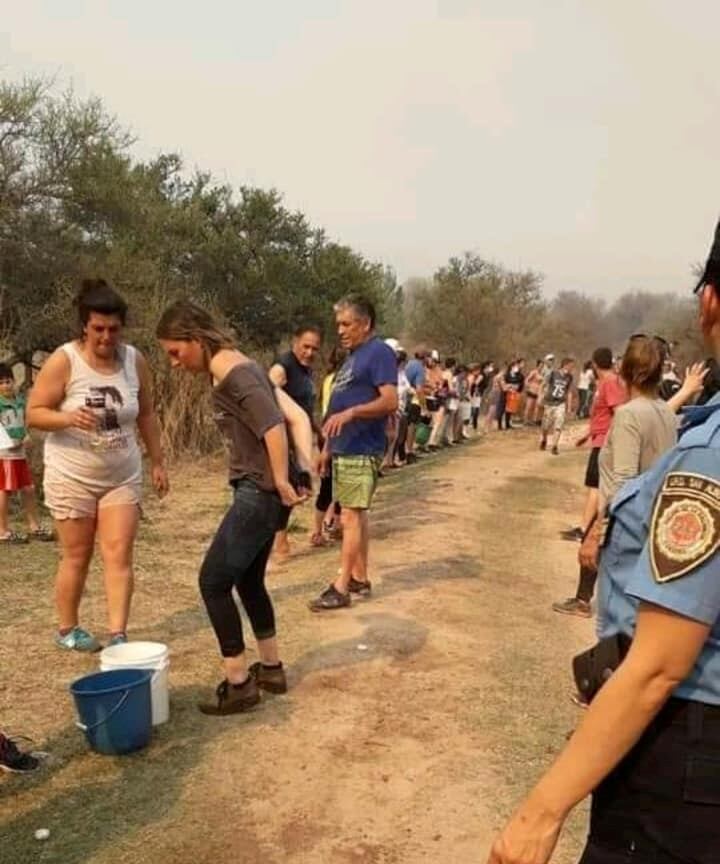 En Mina Clavero se formó un corredor humano de acarreo de agua para combatir los incendios. (Belen Intima)