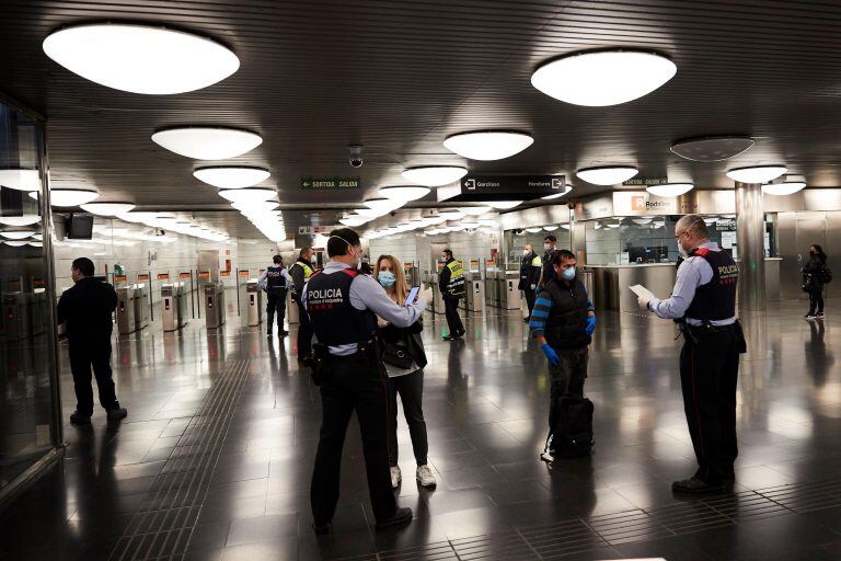 Los Mossos d'Esquadra realizan controles de movilidad en el Metro de Barcelona donde voluntarios de Protección Civil y de Cruz Roja, reparten mascarillas (EFE)