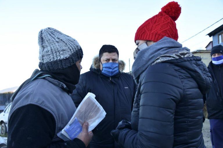 Lorena Henriques Sanches junto a funcionarios del Municipio acercando agua y leña