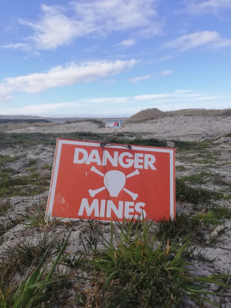 "Peligro / Minas ". Uno de los tantos carteles, que por tantos años estuvieron colocados en diferentes partes de las islas, donde las fuerzas armadas argentinas habían colocado explosivos durante la guerra del '82, contra posibles desembarco de tropas británicas. La guerra terminó el 14 de junio del '82, pero las minas quedaron, constituyéndose en un constante peligro para los habitantes y también para visitantes.