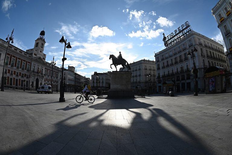 -FOTODELDIA- GRAF9267. MADRID, 11/04/2020.- Un repartidor cruza en bicicleta la Puerta del Sol, en Madrid, en una jornada de Sábado Santo en la que las muertes diarias causadas por la COVID-19 bajaron por tercera jornada consecutiva en España, que cumple cuatro semanas de medidas de confinamiento de la población. EFE/Fernando Villar