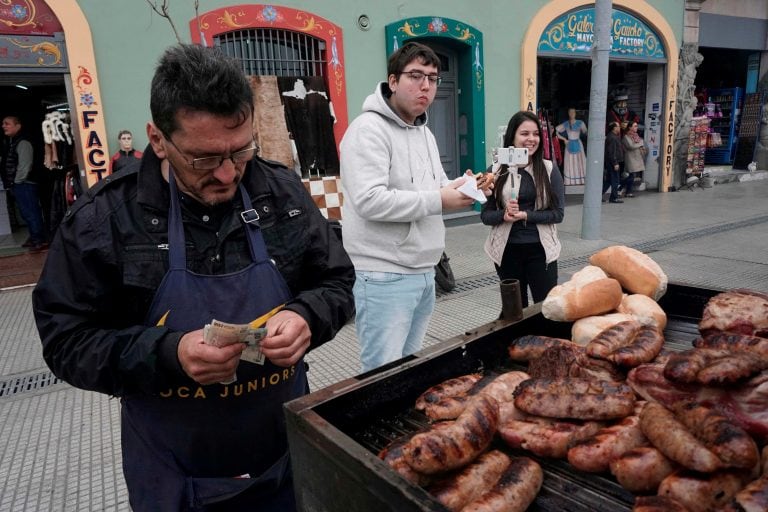 Un turista come un choripán durante una visita al tradicional Caminito en el barrio de La Boca, en Buenos Aires. Crédito: Eitan ABRAMOVICH / AFP.