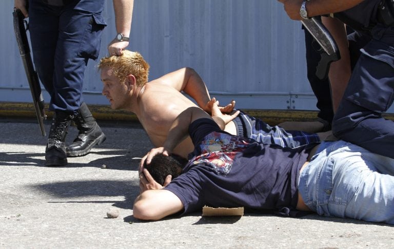 A police officer grabs a man by his hair as he and another man are detained by police outside a supermarket that was being looted in Cordoba, Argentina, Wednesday, Dec. 4, 2013. A police strike for higher pay has prompted waves of looting and robberies in Argentina's second largest city. The violence in Cordoba began Tuesday night and continued Wednesday morning, with storefronts being shattered, mobs stealing merchandise, robbers attacking people in the streets and vigilantes arming themselves to protect their homes. (AP Photo/Mario Sar) cordoba  saqueos en cordoba por acuartelamiento de la policia en reclamo de mejora salarial reclamo salarial policias cordoba asamblea policias acuartelados reclamos