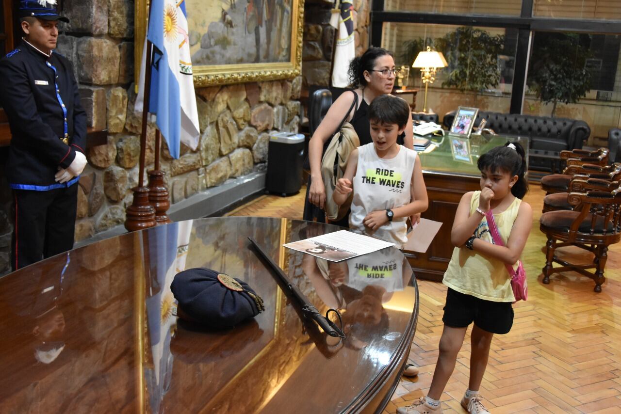 En primer plano y custodiados por miembros de la Guardia Histórica, el sable y la gorra del general Manuel Eduardo Arias que se conserva en la Legislatura de Jujuy. Detrás de los visitantes se ve el histórico escritorio del primer gobernador jujeño José María Fascio.