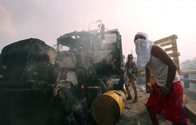 Manifestantes se enfrentan con miembros de la Policía Nacional Bolivariana, junto a un camión que transportaba ayuda humanitaria y fue quemado (EFE/ Mauricio Dueñas Castañeda)