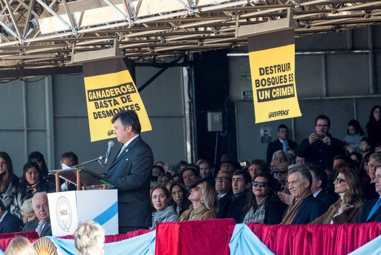 El presidente de la Sociedad Rural Argentina, Daniel Pelegrina, pronuncia un discurso junto al presidente de Argentina Mauricio Macri en medio de carteles desplegados por la organización Greenpeace en el acto inaugural de la Exposición Rural en Buenos Aires. Crédito: EFE/ GREENPEACE.