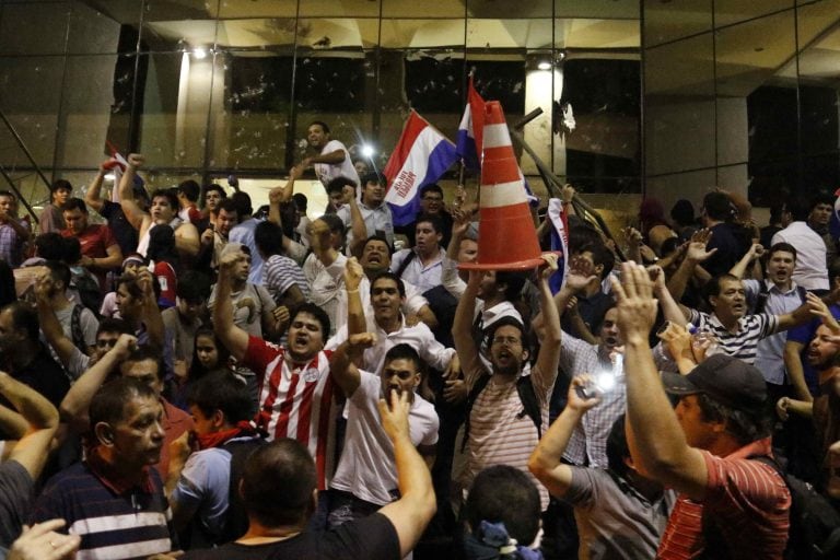 ASU48. ASUNCIÓN (PARAGUAY), 31/03/2017.- Manifestantes gritan consignas hoy, viernes 31 de marzo de 2017, afuera de la sede del Congreso Nacional en Asunción (Paraguay). Grupos de manifestantes y agentes de la Policía Nacional mantienen enfrentamientos fr