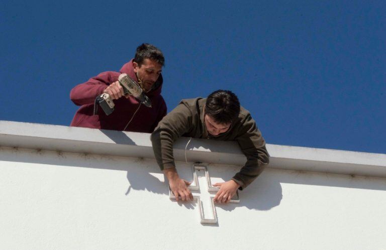 Los chicos instalando la cruz lumínica en la fachada del hospital