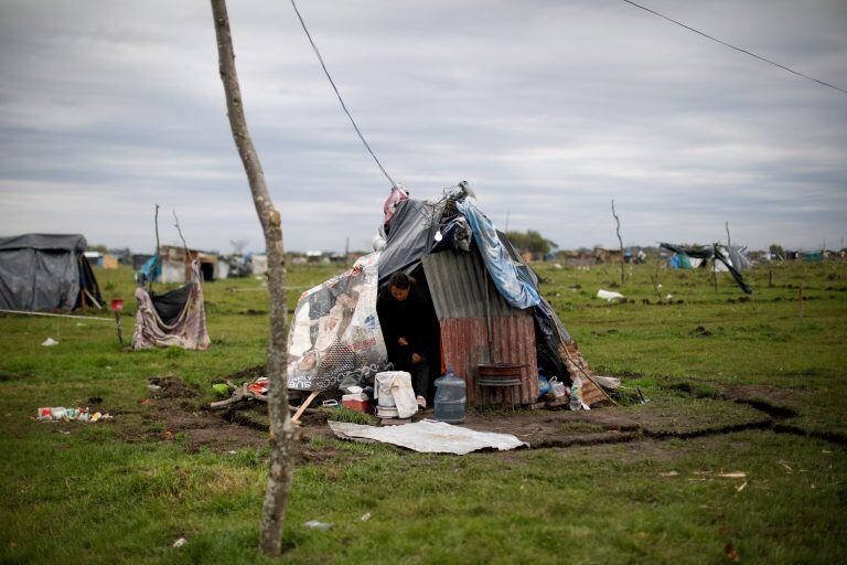 Martina leaves her makeshift home at a squatters camp in Guernica, Buenos Aires province, Argentina, Thursday, Oct. 1, 2020. A court has ordered the eviction of families who are squatting here since July, but the families say they have nowhere to go amid the COVID-19 pandemic. (AP Photo/Natacha Pisarenko)