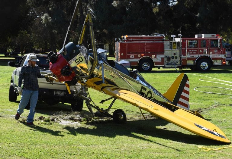 (FILES) This file photo taken on March 6, 2015 shows firefighters and an aviation official remove the 1942 Ryan Aeronautical ST3KR plane that crashed onto a golf course and was piloted by US actor Harrison Ford in Venice, California. 
Hollywood star Harrison Ford was involved in a near-miss at a California airport on Febuary 14, 2017 as he was piloting his private plane, officials and US media said. Ford, a seasoned pilot and vintage plane collector, was approaching John Wayne Airport in Orange County, NBC reported, when he headed towards a taxiway rather than the runway, passing over a Boeing 737 with 110 passengers and six crew. / AFP PHOTO / MARK RALSTON