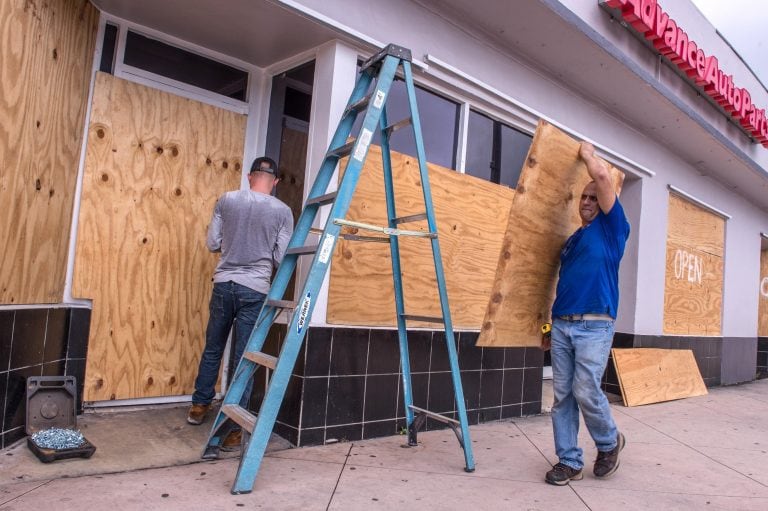 Empleados cubren el local con tablones de madera por la llegada del huracán Dorian. (EFE)