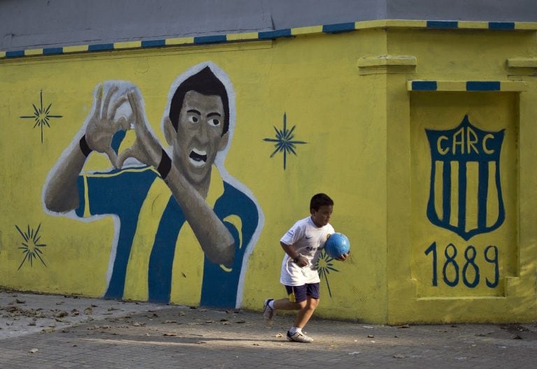 A kid holding a ball runs past a mural depicting Argentine footballer Angel Di Maria painted in a corner near the Gigante de Arroyito stadium of Rosario Central football club in Rosario, Santa Fe province, some 350 km northwest of Buenos Aires on April 5, 2015. AFP PHOTO / HECTOR RIO baigorria santa fe  ex futbolista argentino mural pintura futbol simpatizantes de angel Di Maria