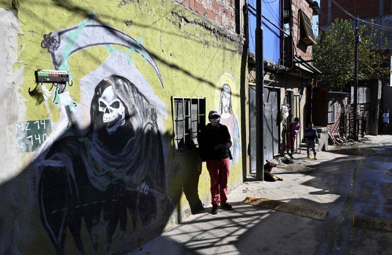 Un hombre espera junto a una pintada de San La Muerte en el barrio Padre Carlos Mugica en la Villa 31 (Foto: JUAN MABROMATA / AFP)