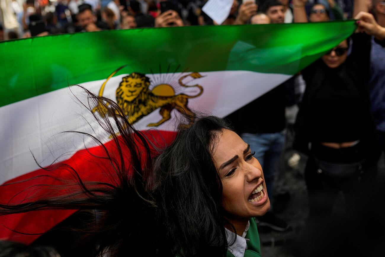 Una mujer grita consignas junto a una bandera iraní afuera del consulado general de Irán en Estambul, Turquía.