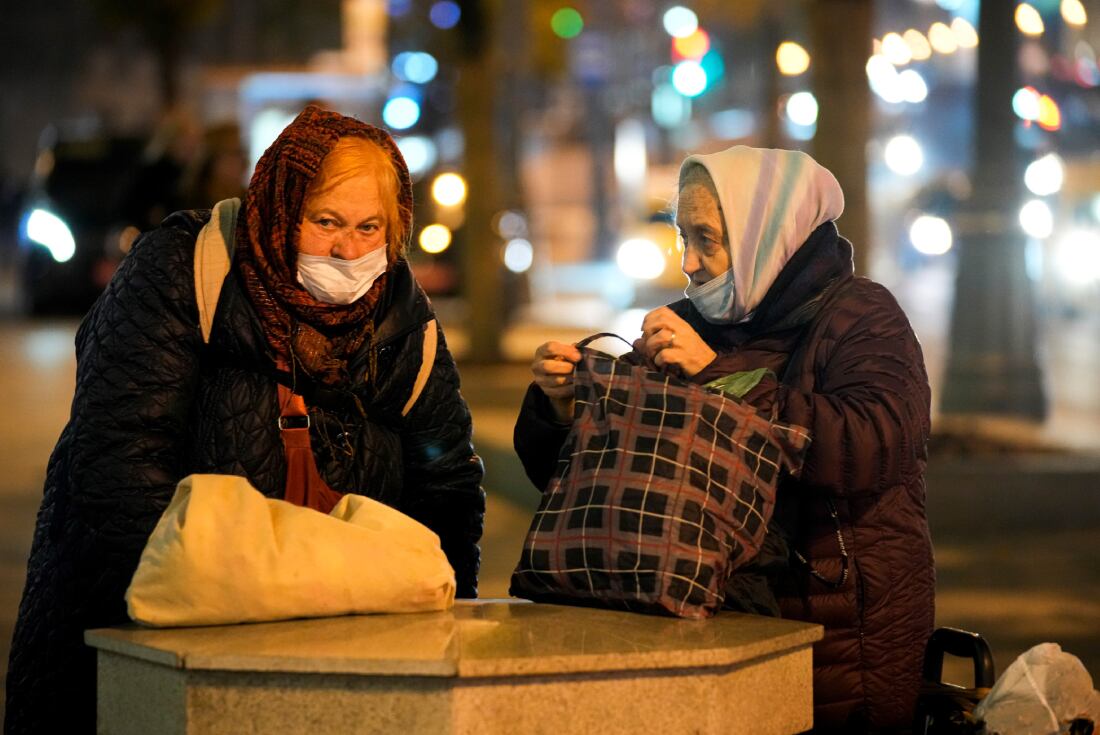 Dos ancianas que usan mascarillas para protegerse contra el coronavirus hablan entre sí en un árbol de la Plaza Roja, en Moscú. (AP)