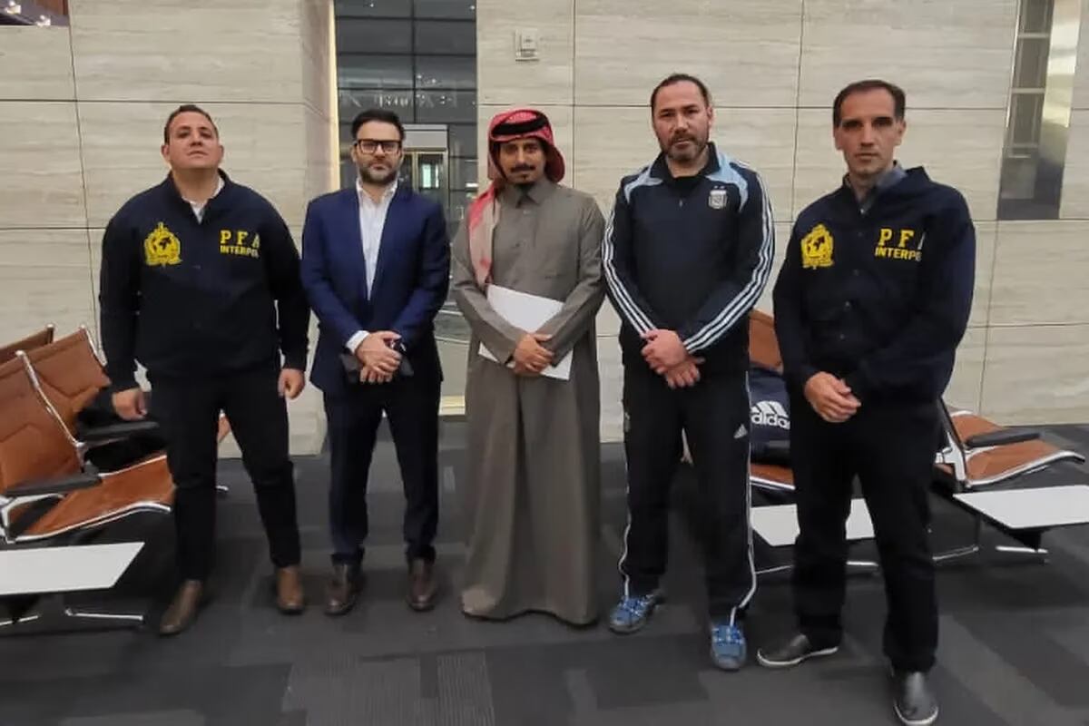 Diego Chacón (segundo de la izquierda) vestido con la indumentaria oficial de la Selección Argentina de Fútbol, posando para la fotografía en el aeropuerto de Doha previo a su extradición a la Argentina custodiado por efectivos de Interpol.