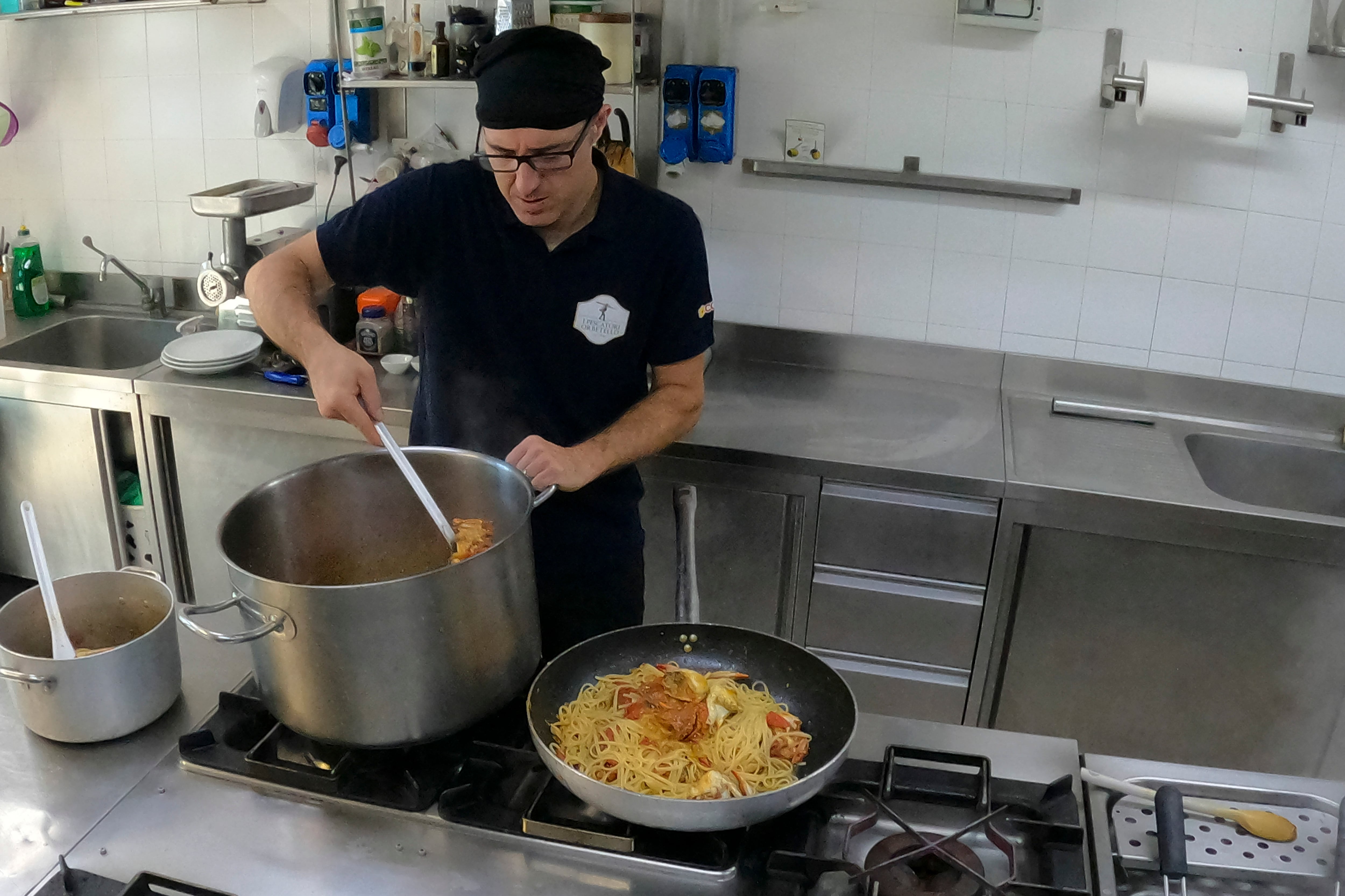 Un cocinero prepara pasta con cangrejo azul en un restaurante de Orbetello, Italia, el lunes 14 de agosto de 2023. (AP Foto/Luigi Navarra)