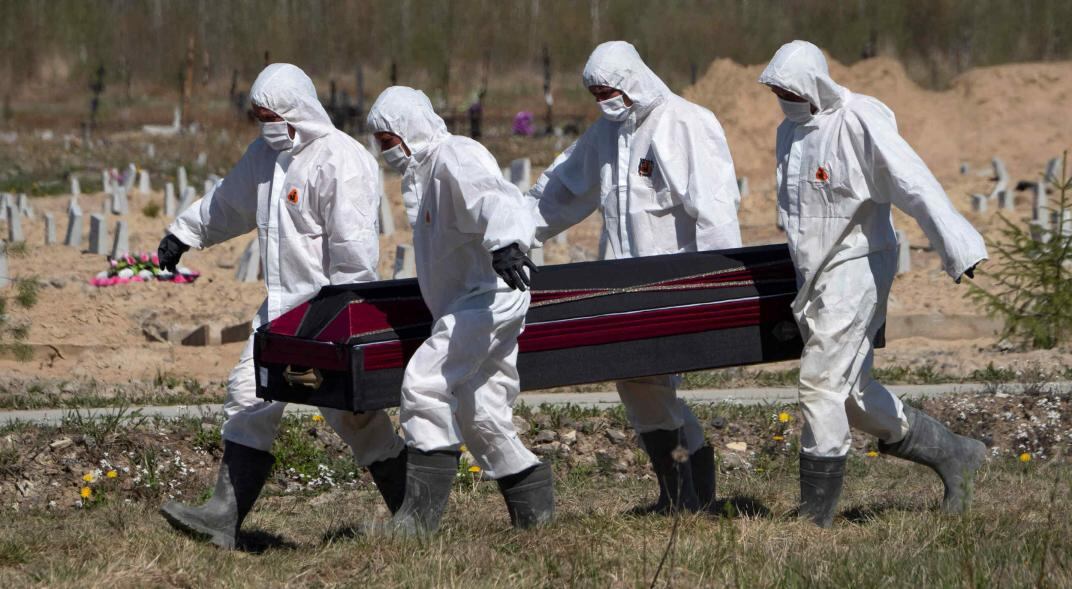 Trabajadores entierran un féretro en la sección especial para el coronavirus del cementerio en Kolpino, en las afueras de San Petersburgo, Rusia. (AP)