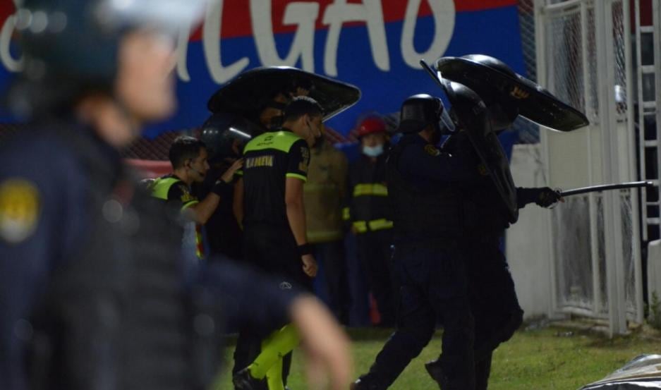 La salida de la cancha del árbitro Leandro Rey Hilfer, en medio de los proyectiles que caían a la cancha. (Diario El Liberal de Santiago del Estero)