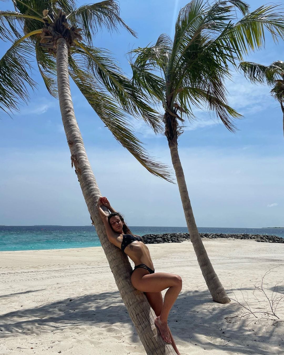 María Pedraza posando sobre una palmera en Maldivas.