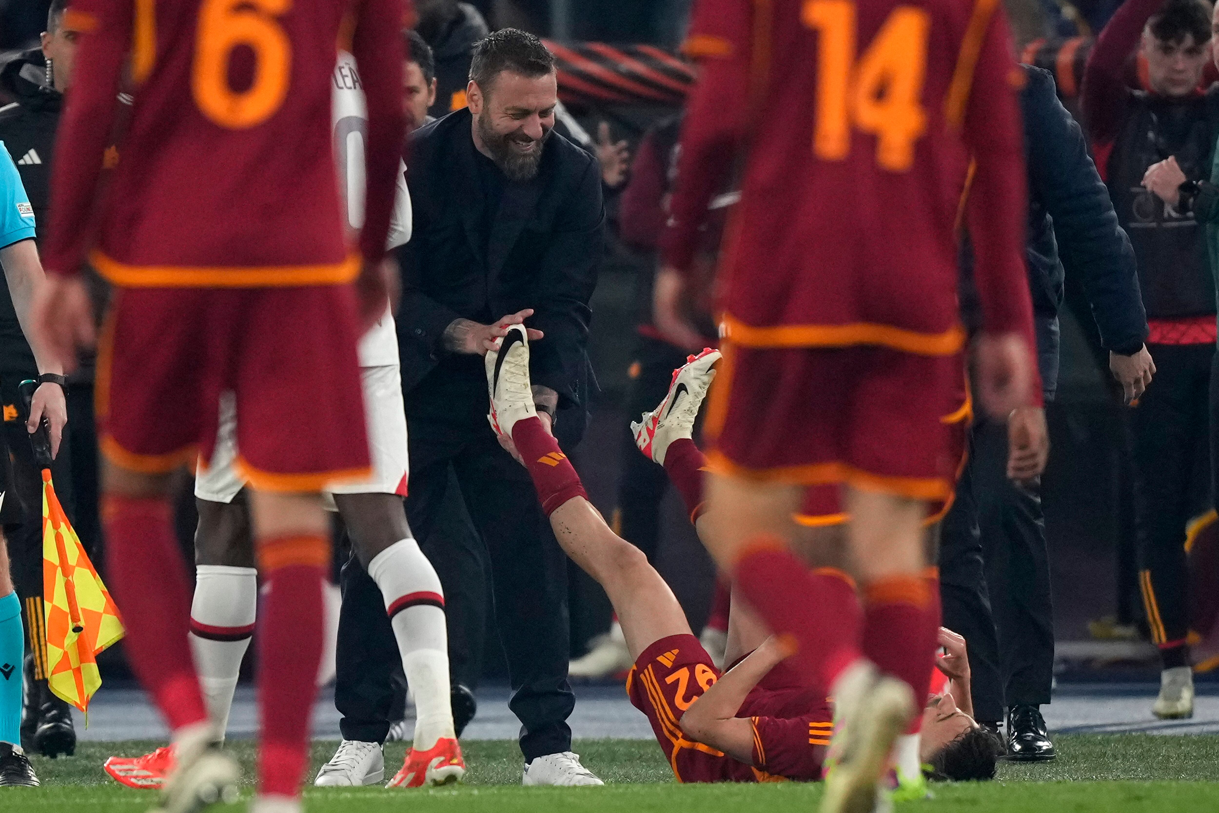 El técnico de la Roma Daniele De Rossi sonríe mientras estira las piernas Stephan El Shaarawy durante el partido de cuartos de final de la Liga Europa contra el AC Milan, el 18 de abril de 2024. (AP Foto/Andrew Medichini)