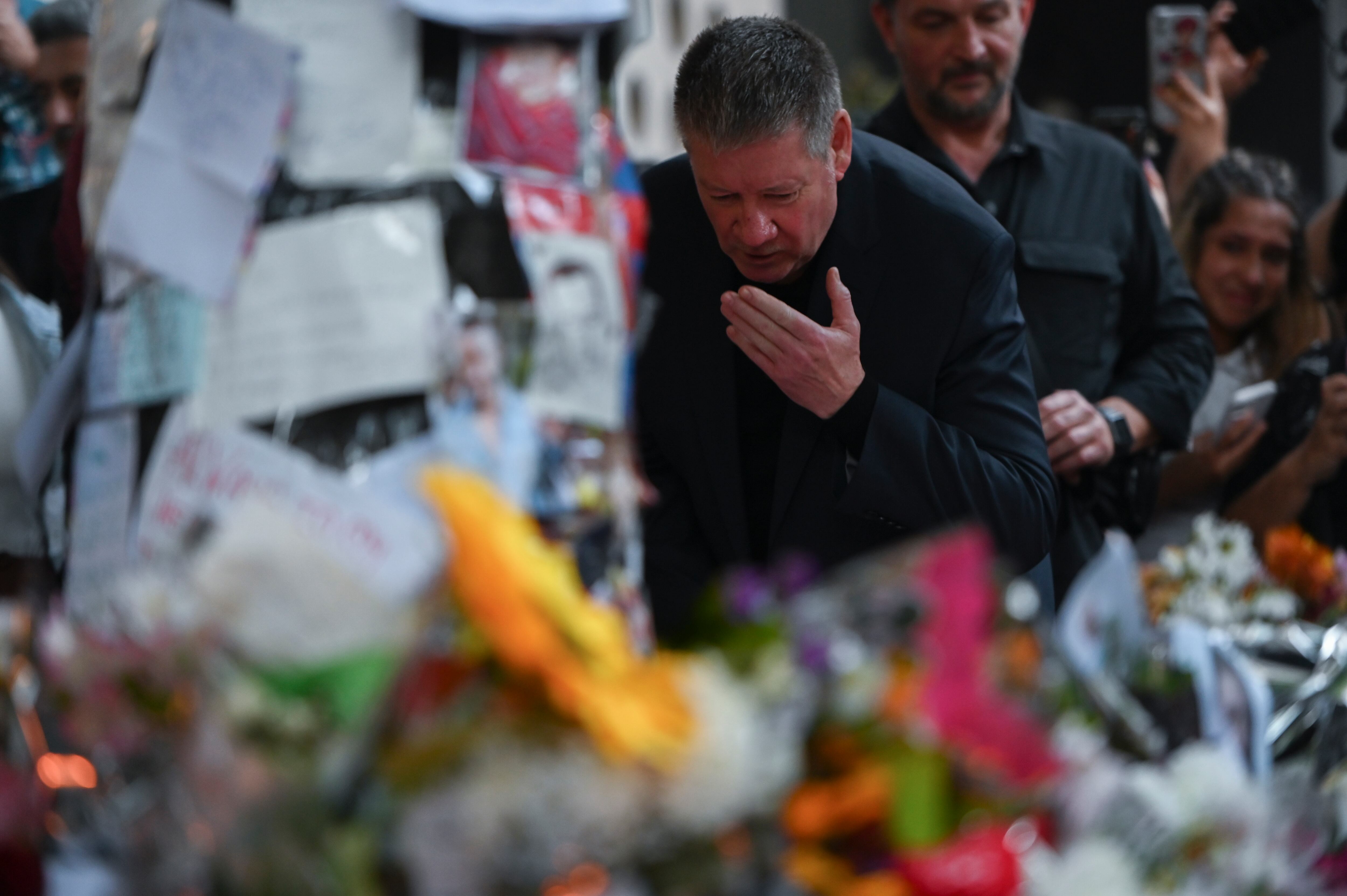 Geoff Payne, a la derecha, padre del exintegrante de One Direction, el cantante Liam Payne, visita un altar improvisado fuera del hotel Casa Sur Hotel donde el artista pop británico murió al precipitarse desde un balcón, en Buenos Aires, Argentina, el viernes 18 de octubre de 2024. (AP Foto/Mario de Fina)