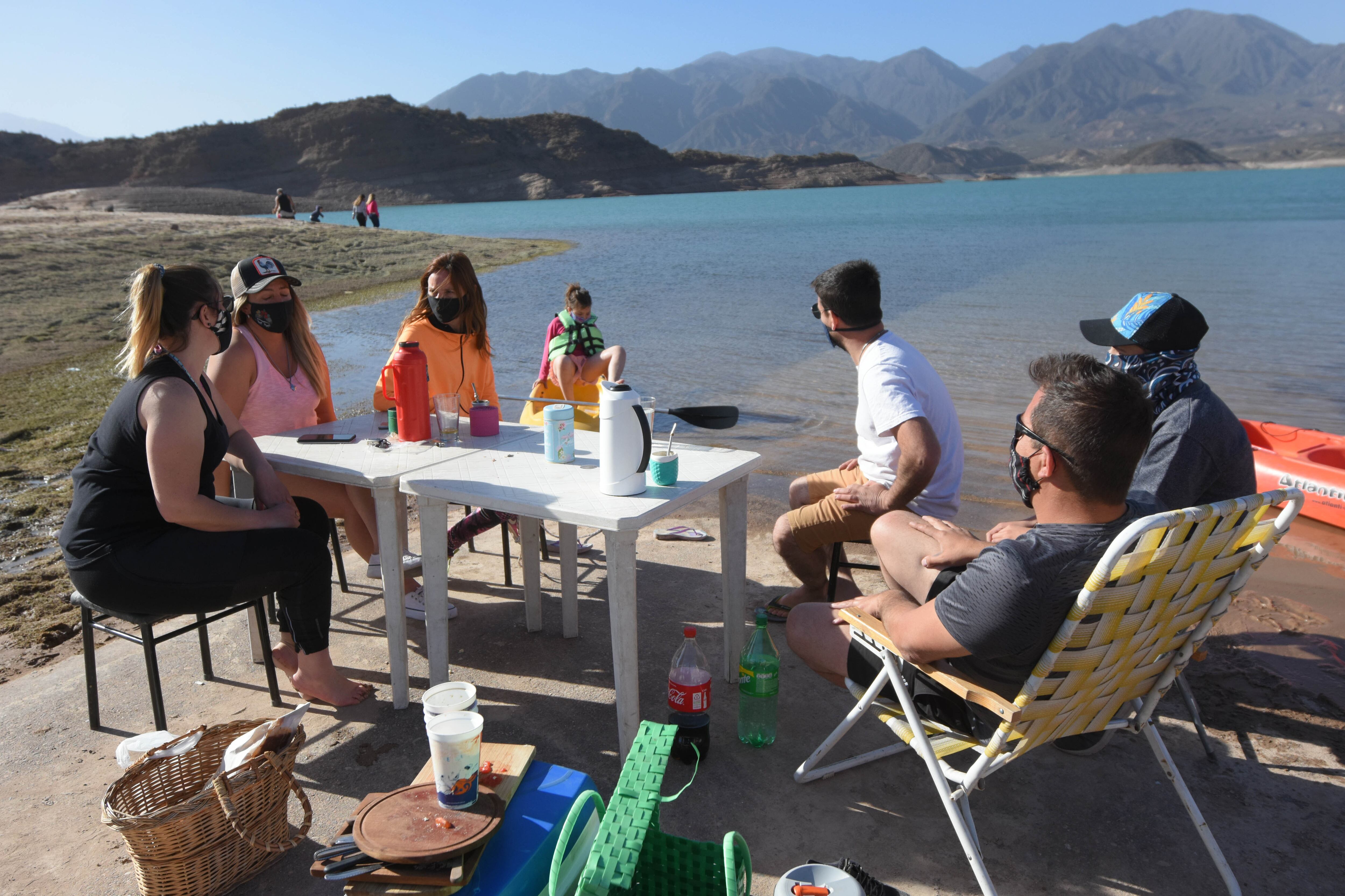 La gente disfruta a la  orilla del espejo de agua del dique Potrerillos.