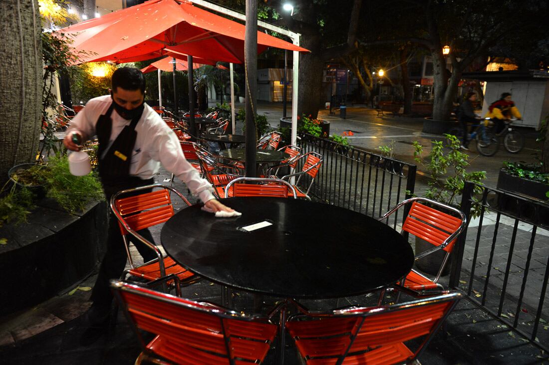 La ciudad vacia horas antes del inicio de las nuevas restricciones a la circulacion y del comienzo de la nueva cuarentena.  Bares y restaurantes cerrados y sin gente en las mesas de la vereda.  
Mozo limpia una mesa en el bar El Ruedo.
( José Gabriel Hernández)