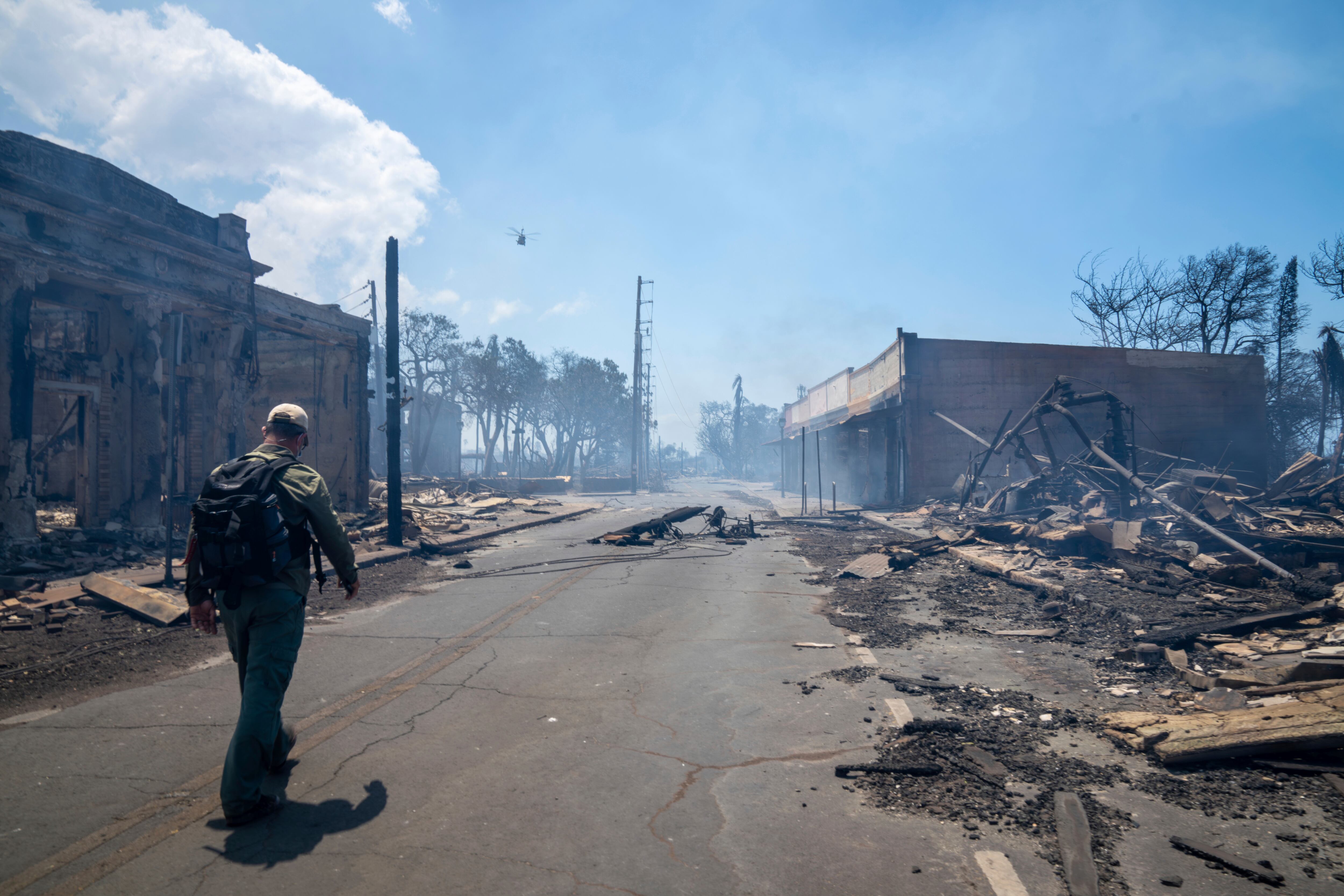 En esta foto proporcionada por Tiffany Kidder Winn, un hombre pasa junto a los restos de un incendio forestal el miércoles 9 de agosto de 2023 en Lahaina, Hawái. (Tiffany Kidder Winn vía AP)