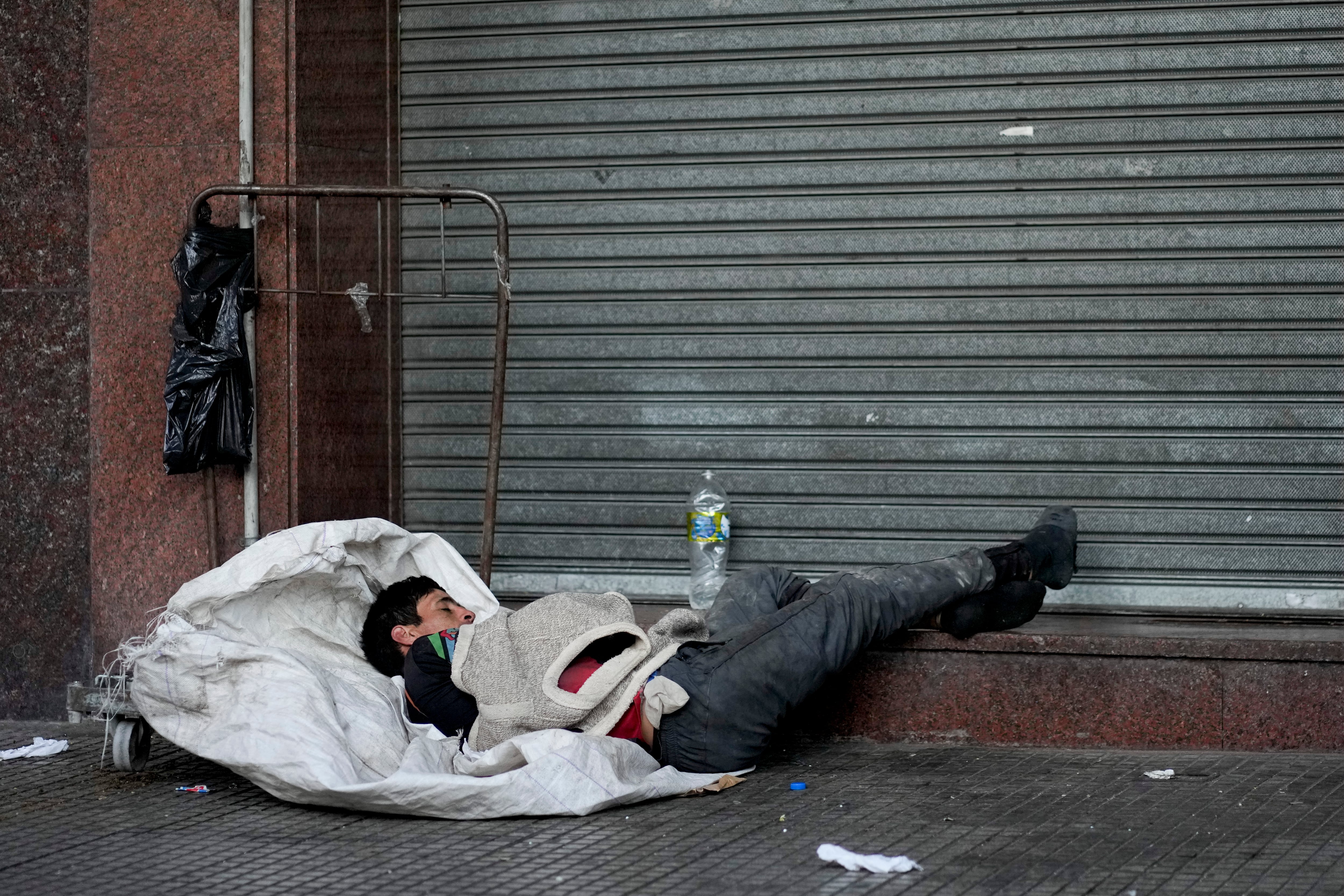 Un reciclador, que recolecta materiales para revender, duerme en su carrito en una acera en Buenos Aires, Argentina, el miércoles 29 de marzo de 2023. (AP foto/Natacha Pisarenko)