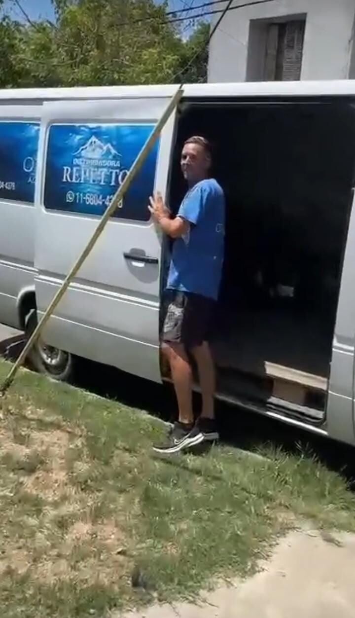 Un sodero llegando a una casa y sacando el bidón de agua.