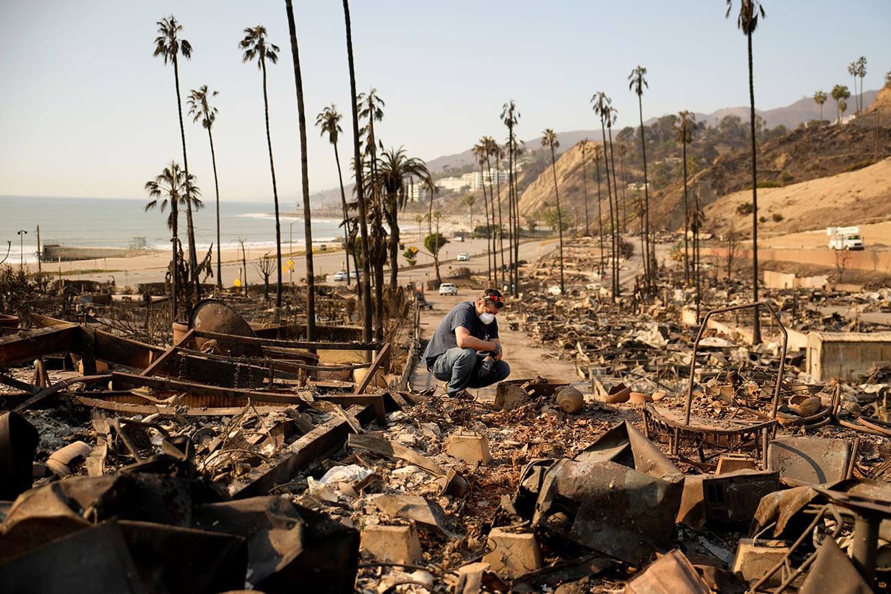 Kevin Marshall examina la propiedad de su madre devastada por el incendio. (AP)