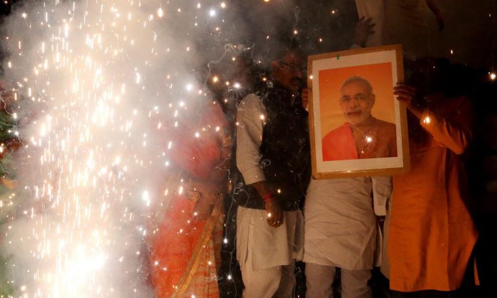 Una persona sostiene una imagen del primer ministro indio, Narendra Modi, mientras varias celebran el bombardeo indio en territorio paquistaní en Bhopal, la India