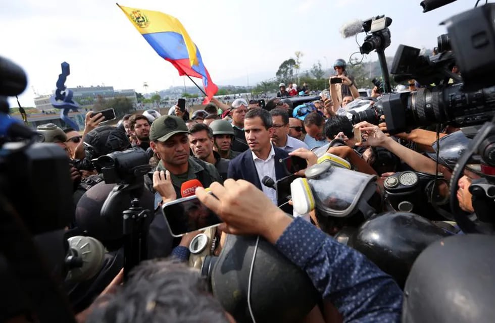 ADDS IDENTIFICATION OF SOLDIER - Venezuela's opposition leader and self-proclaimed president Juan Guaido, center, stands with National Guard Lieutenant Colonel Ilich Sanchez, who is helping to lead a military uprising, center left, as they talk to the press and supporters outside La Carlota air base in Caracas, Venezuela, Tuesday, April 30, 2019. Guaidó took to the streets with activist Leopoldo Lopez and a small contingent of heavily armed troops early Tuesday in a bold and risky call for the military to rise up and oust Maduro. (AP Photo/Fernando Llano)