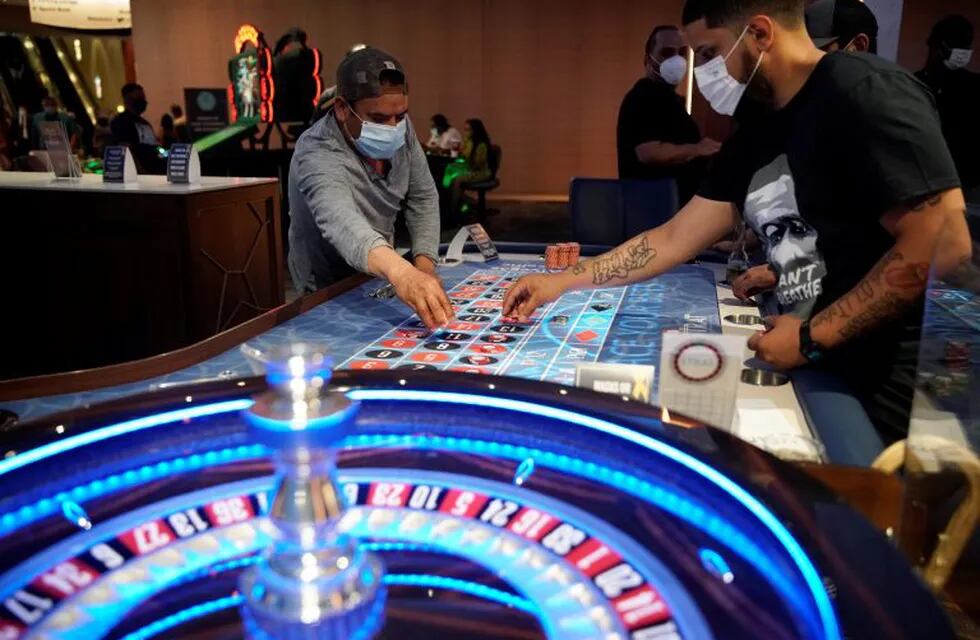 FILE - In this July 4, 2020, file photo, people wear face masks as a precaution against the coronavirus as they play roulette on the Fourth of July at the Strat hotel-casino in Las Vegas. The coronavirus and efforts to fight it have hit U.S. casinos and legal gambling businesses hard. The American Gaming Association on Thursday, Aug. 13, 2020, reported a nearly 79% drop in commercial gambling revenues for the second quarter of 2020. (AP Photo/John Locher, File)