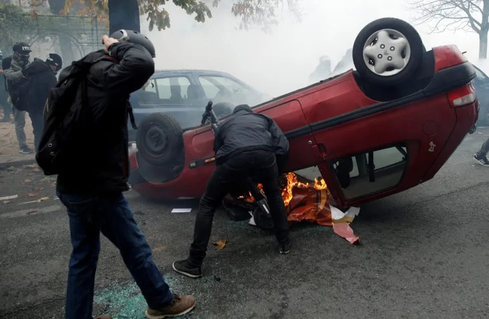 Manifestantes enmascarados volcan un automóvil mientras chocan con la policía antidisturbios durante la manifestación en París , Francia, 16 de noviembre de 2019. Crédito: EFE / EPA / YOAN VALAT.