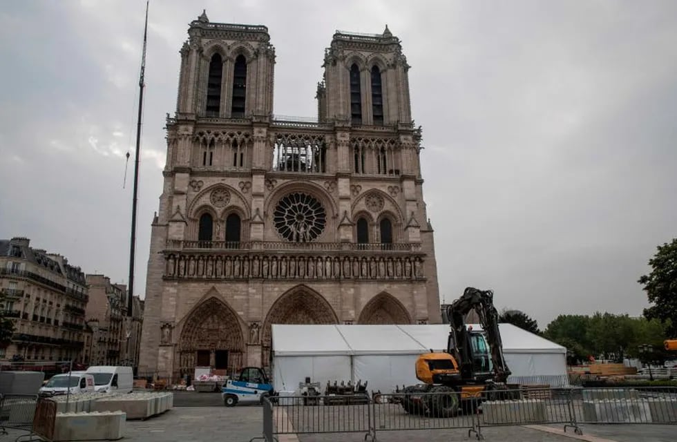 This picture taken on May 2, 2019 in Paris shows an excavator and construction material in front of Notre-Dame de Paris cathedral two weeks after a fire devastated it. (Photo by Thomas SAMSON / AFP)